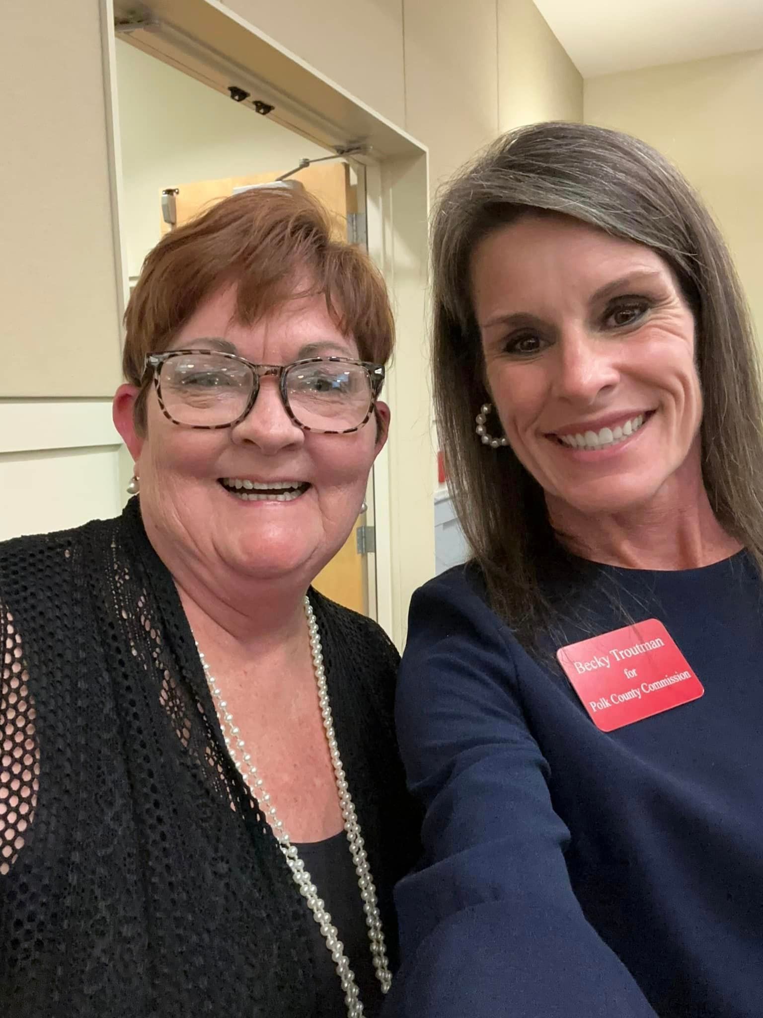Two women are posing for a picture together and smiling for the camera.