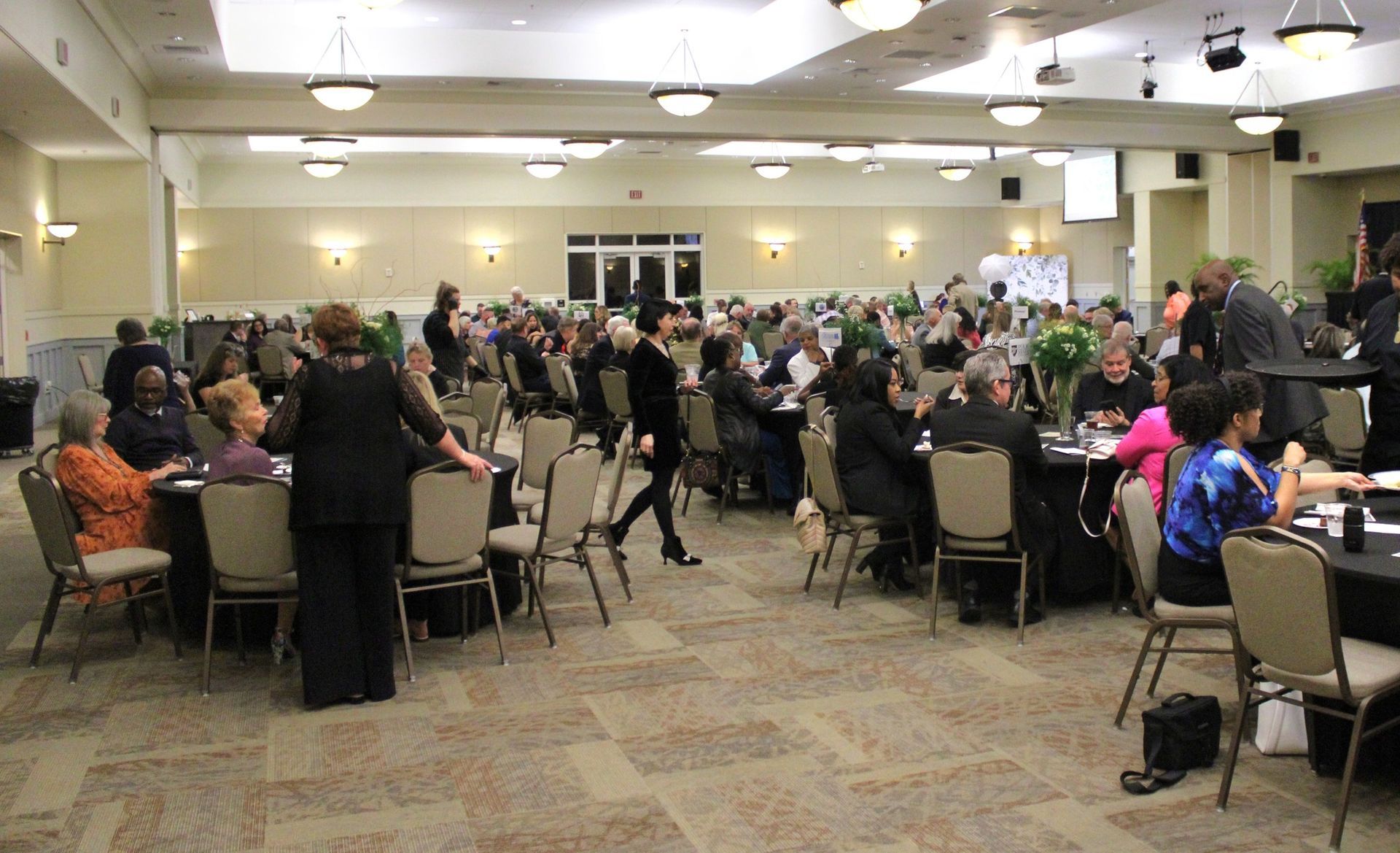 A large room filled with people sitting at tables and chairs.
