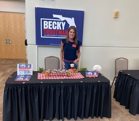 A woman is standing in front of a table with a sign that says becky troutman