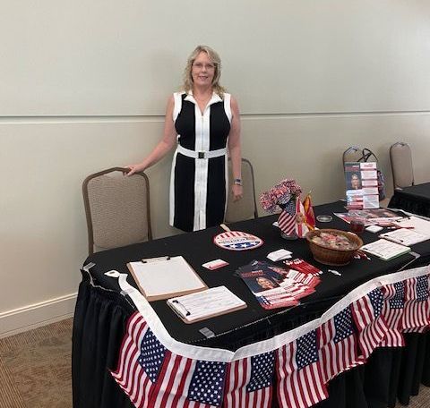 A woman is standing in front of a table decorated with american flags.