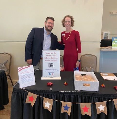 A man and a woman are standing next to each other at a table.