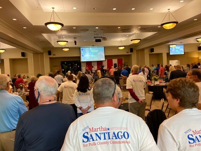 A group of people wearing martha santiago shirts are standing in a room