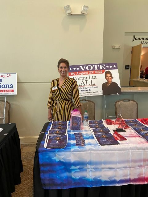 A woman is standing in front of a table with a sign that says vote