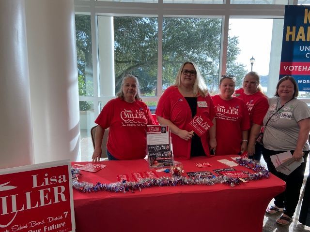 A group of women standing around a table with a sign that says lisa miller