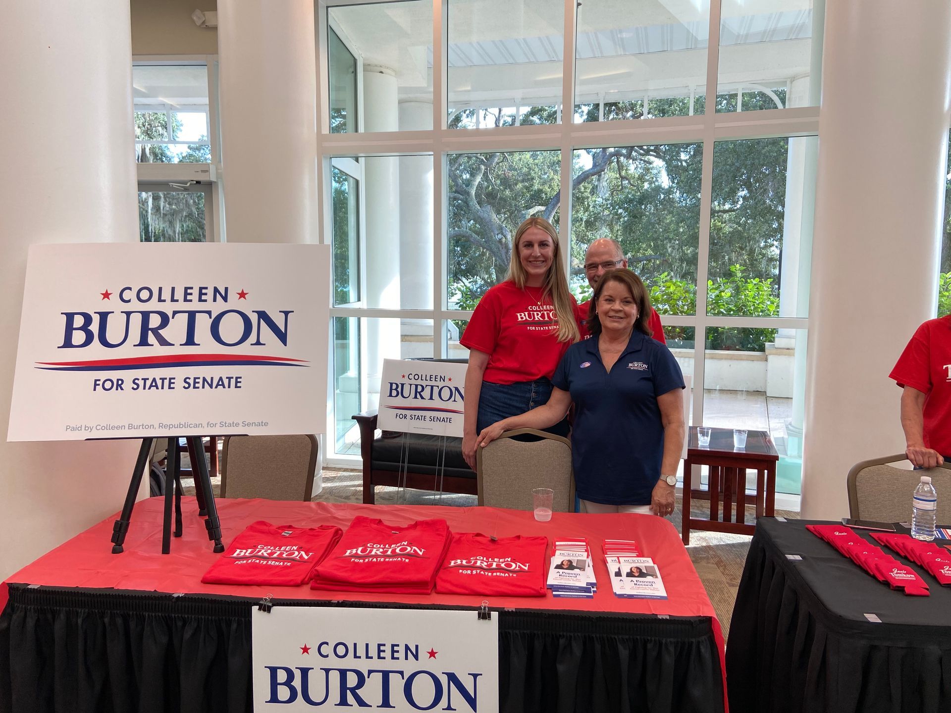 A group of people standing around a table with a sign that says colleen burton