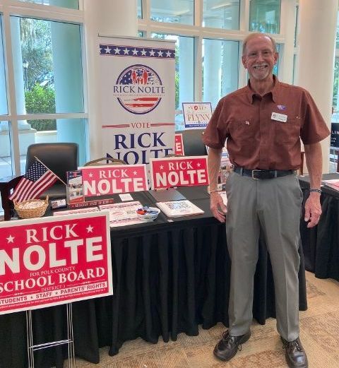 A man stands in front of a table with rick nolte signs on it