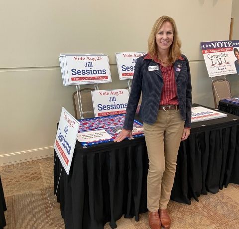 A woman is standing in front of a table with a sign that says no sessions.