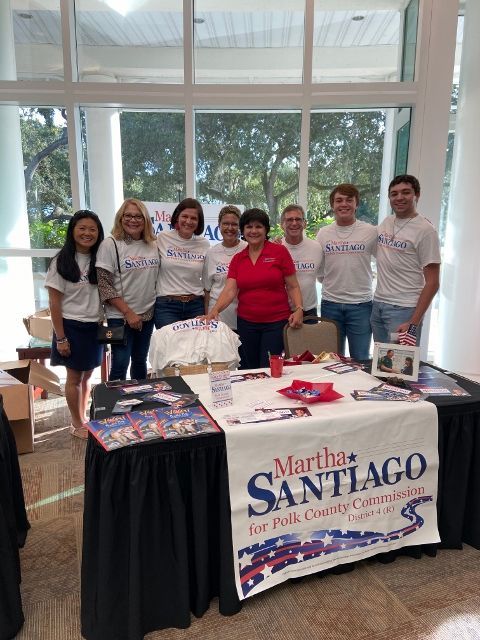 A group of people standing around a table with a sign that says martha santiago