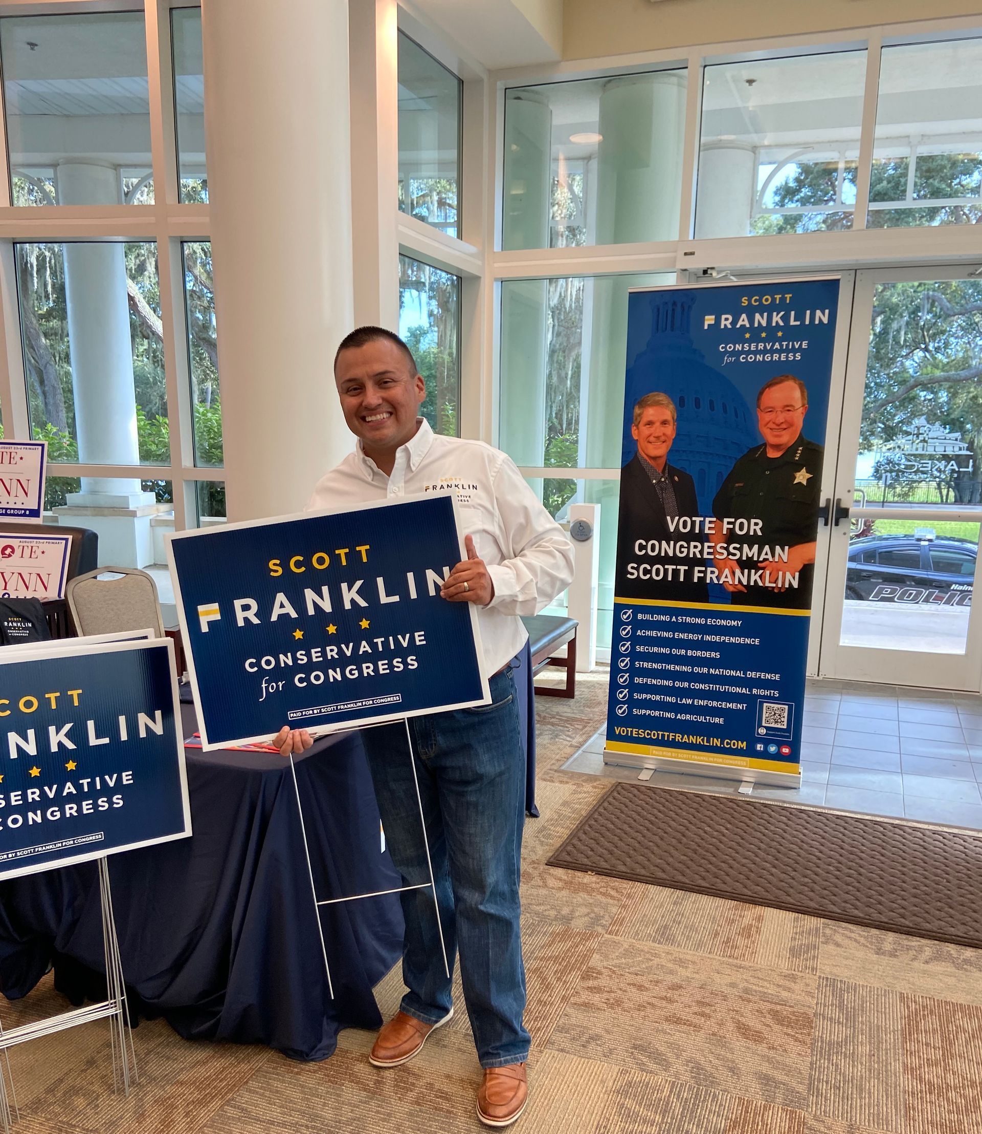 A man is holding a sign that says scott franklin in a room.