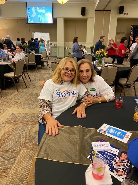 Two women are posing for a picture while wearing santiago shirts