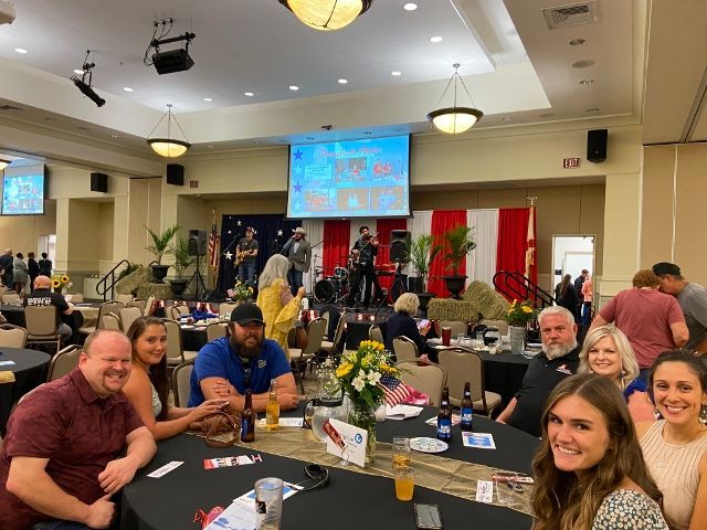 A group of people are sitting at tables in a large room.