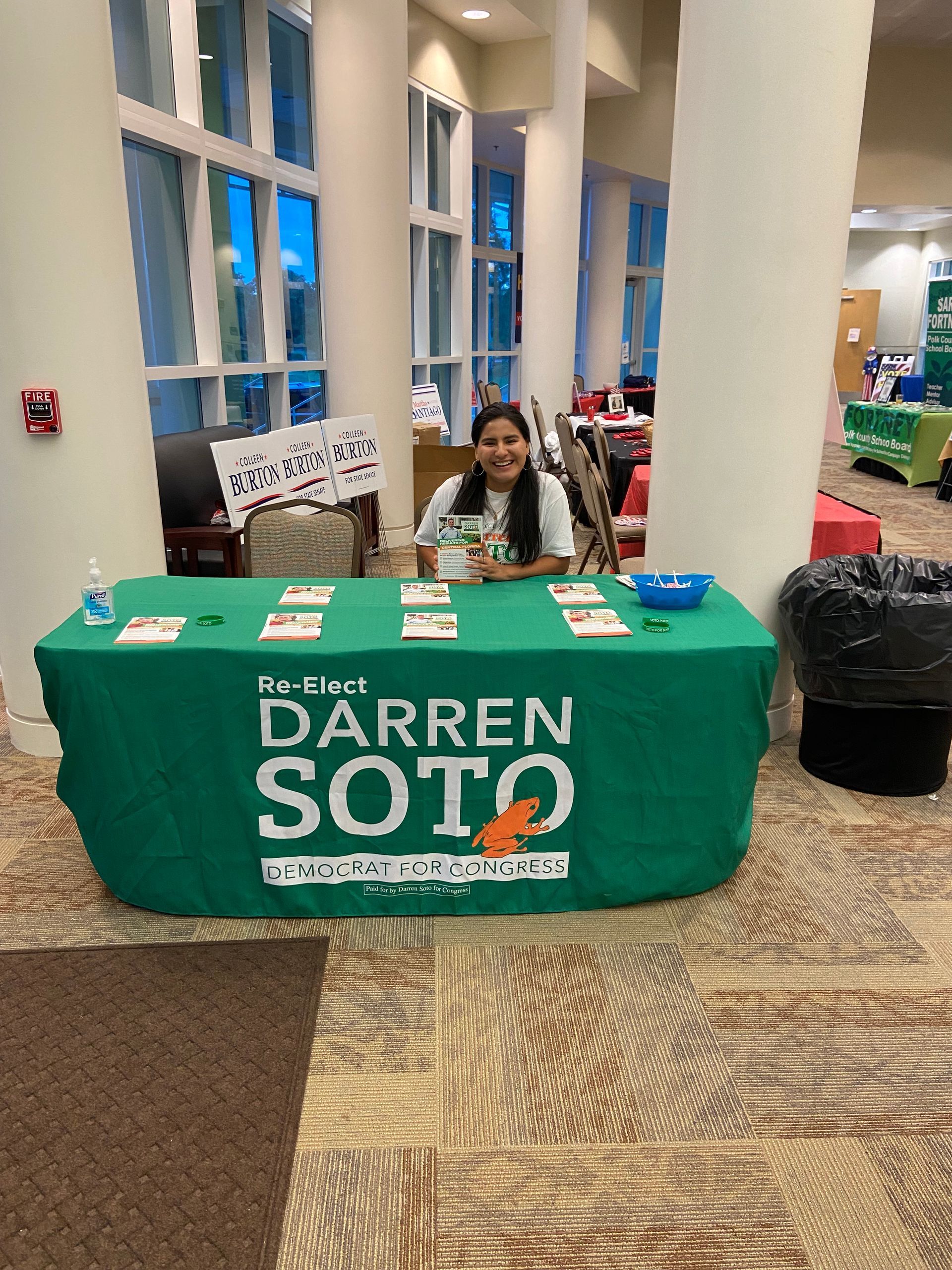A woman is sitting at a table with a green table cloth that says darren soto.