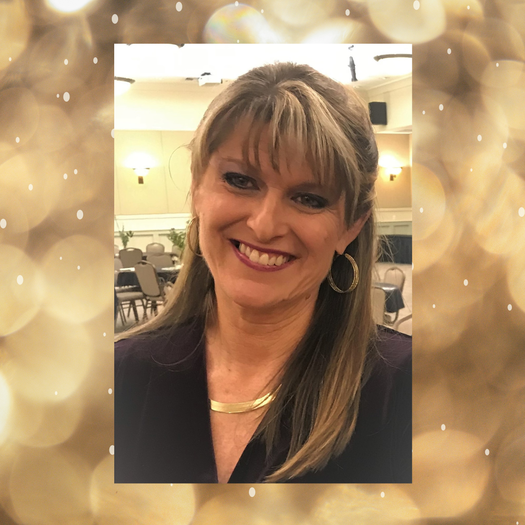 A woman is smiling in front of a gold background