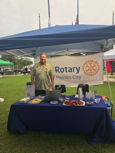 A man standing in front of a table with a sign that says rotary haines city
