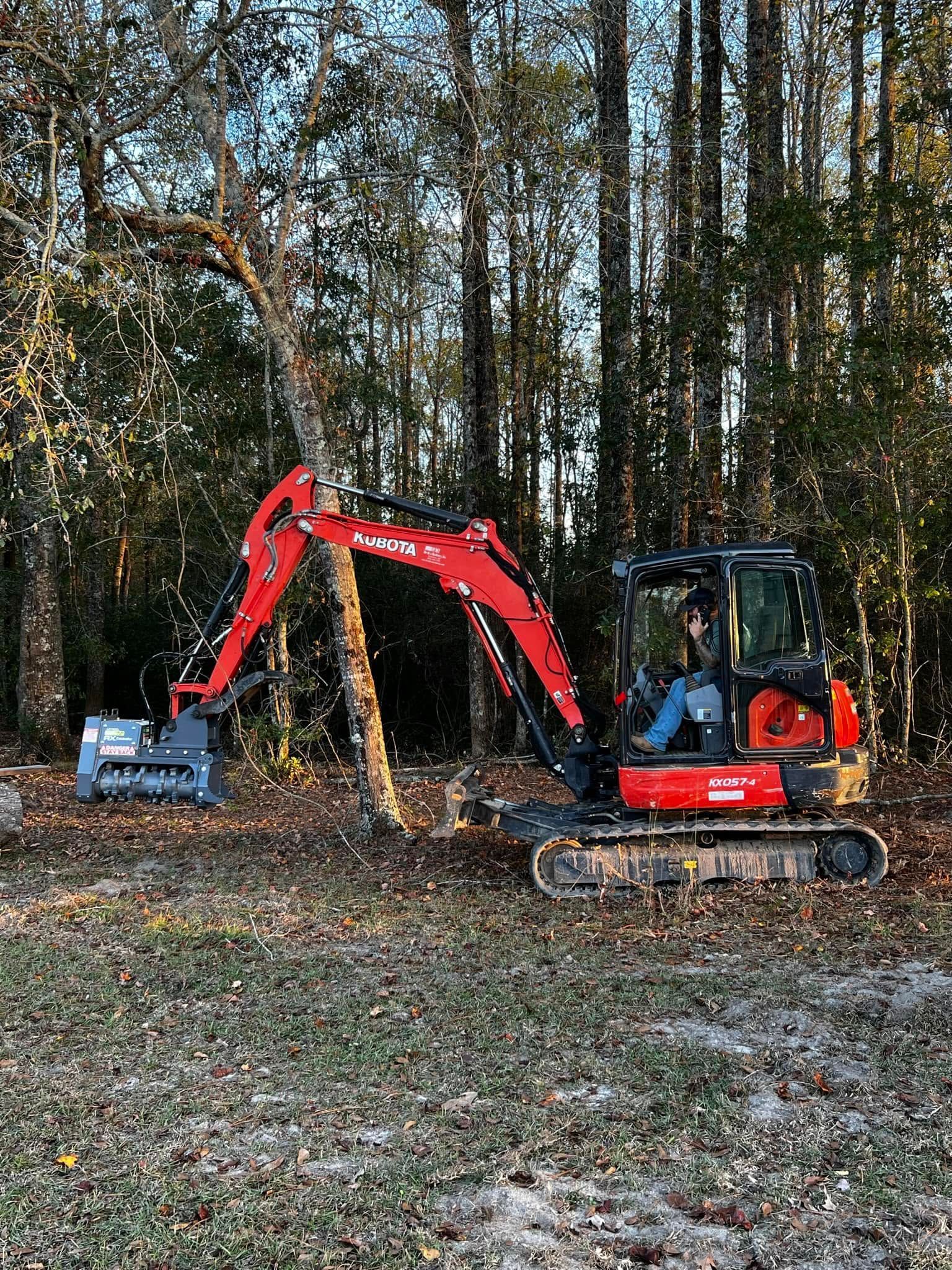 Red mini excavator digging in a wooded area with fallen leaves and trees in the background