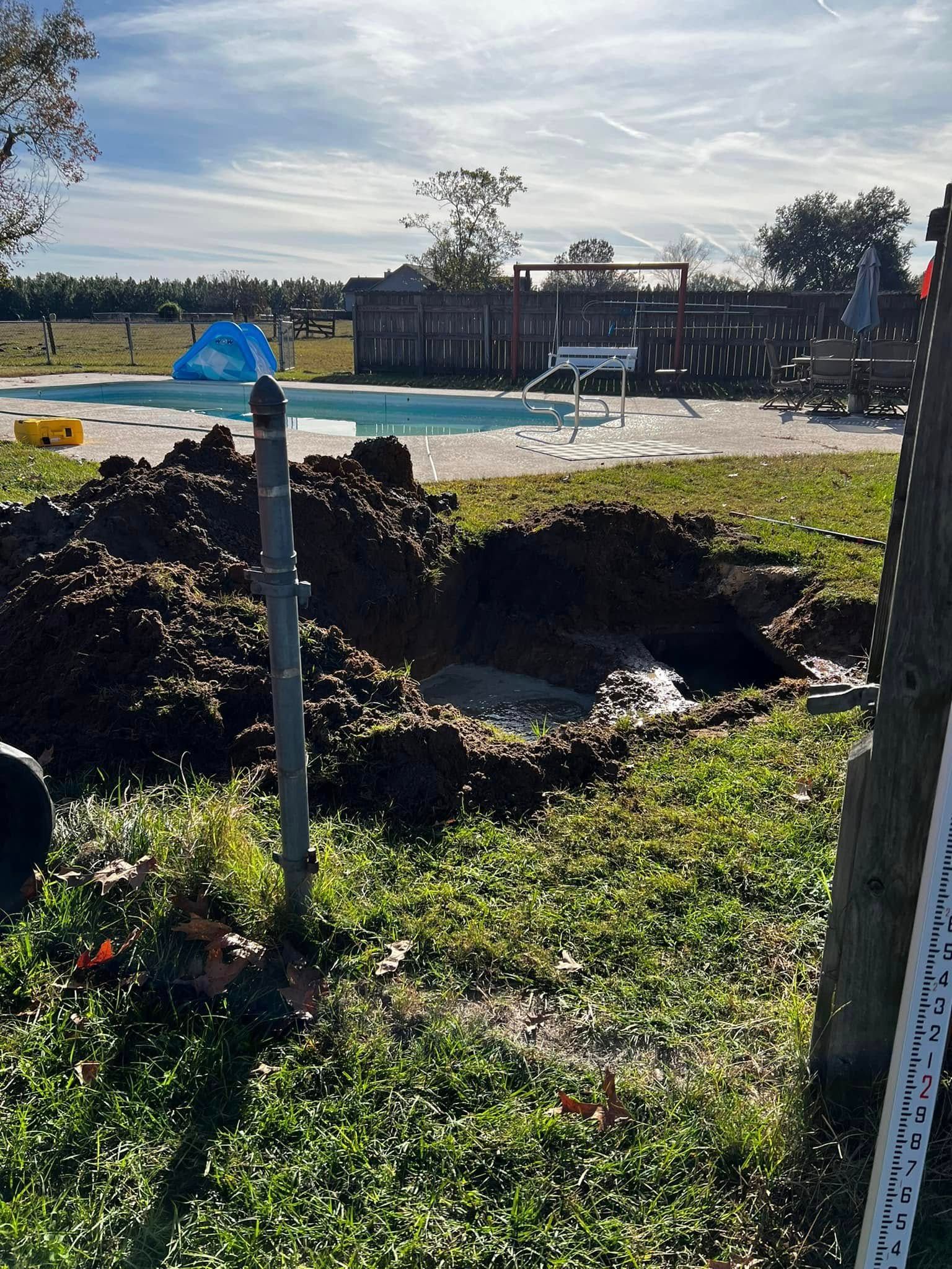 Broken ground near a fenced playground, with a blue post marker and a building in the background
