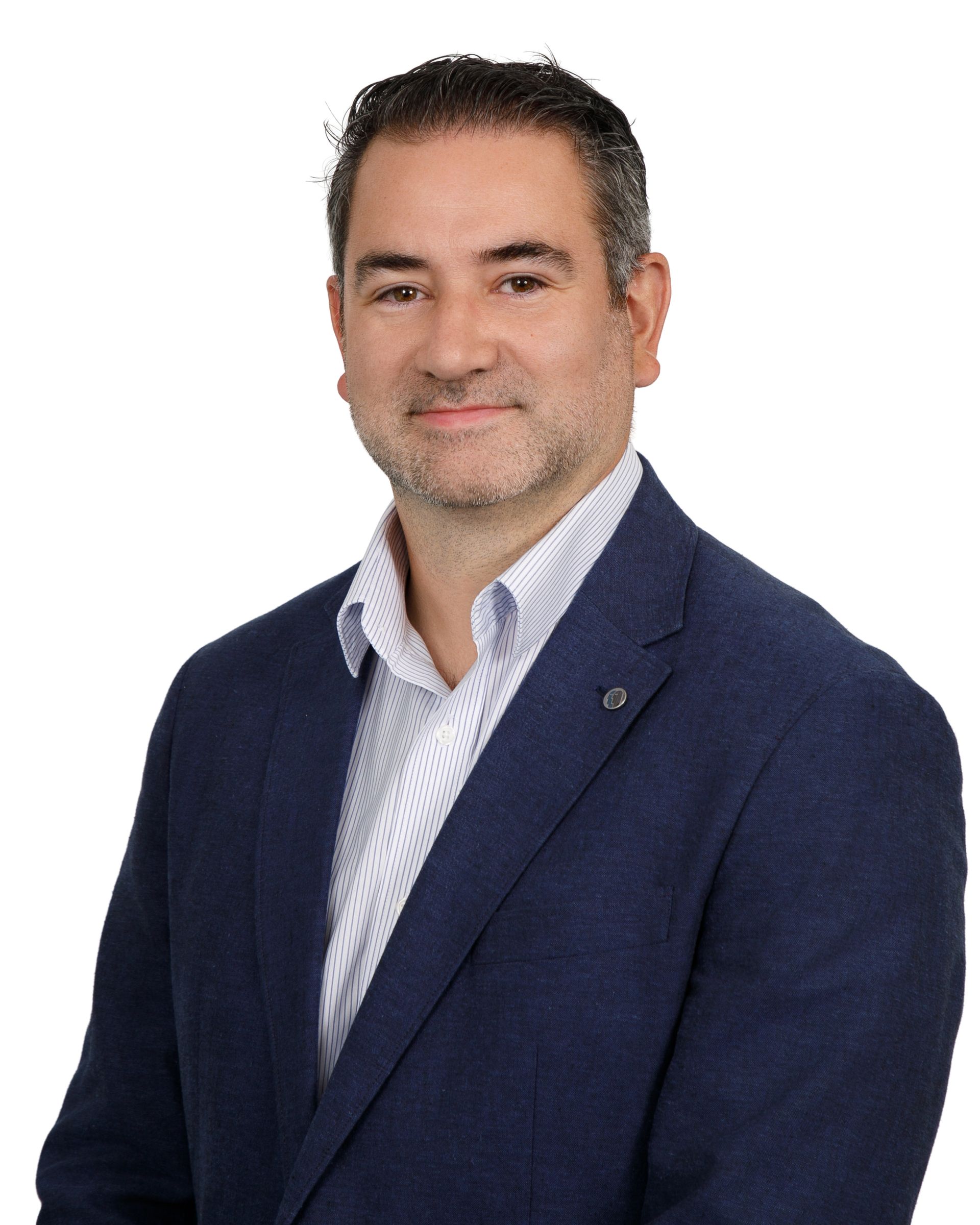 Studio portrait of a person in a navy blazer and light blue shirt against a white background