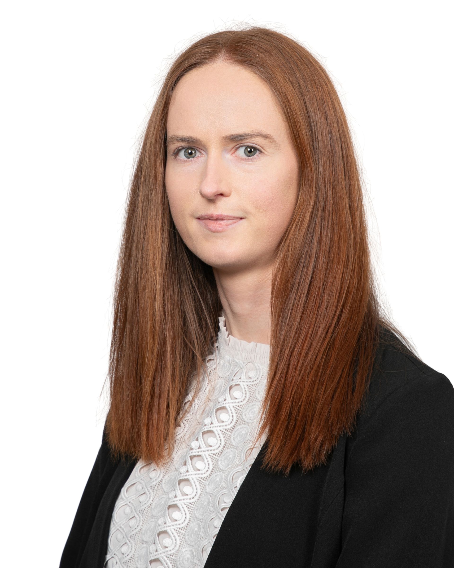 Portrait of a person with long red hair wearing a black blazer and white blouse on a white background
