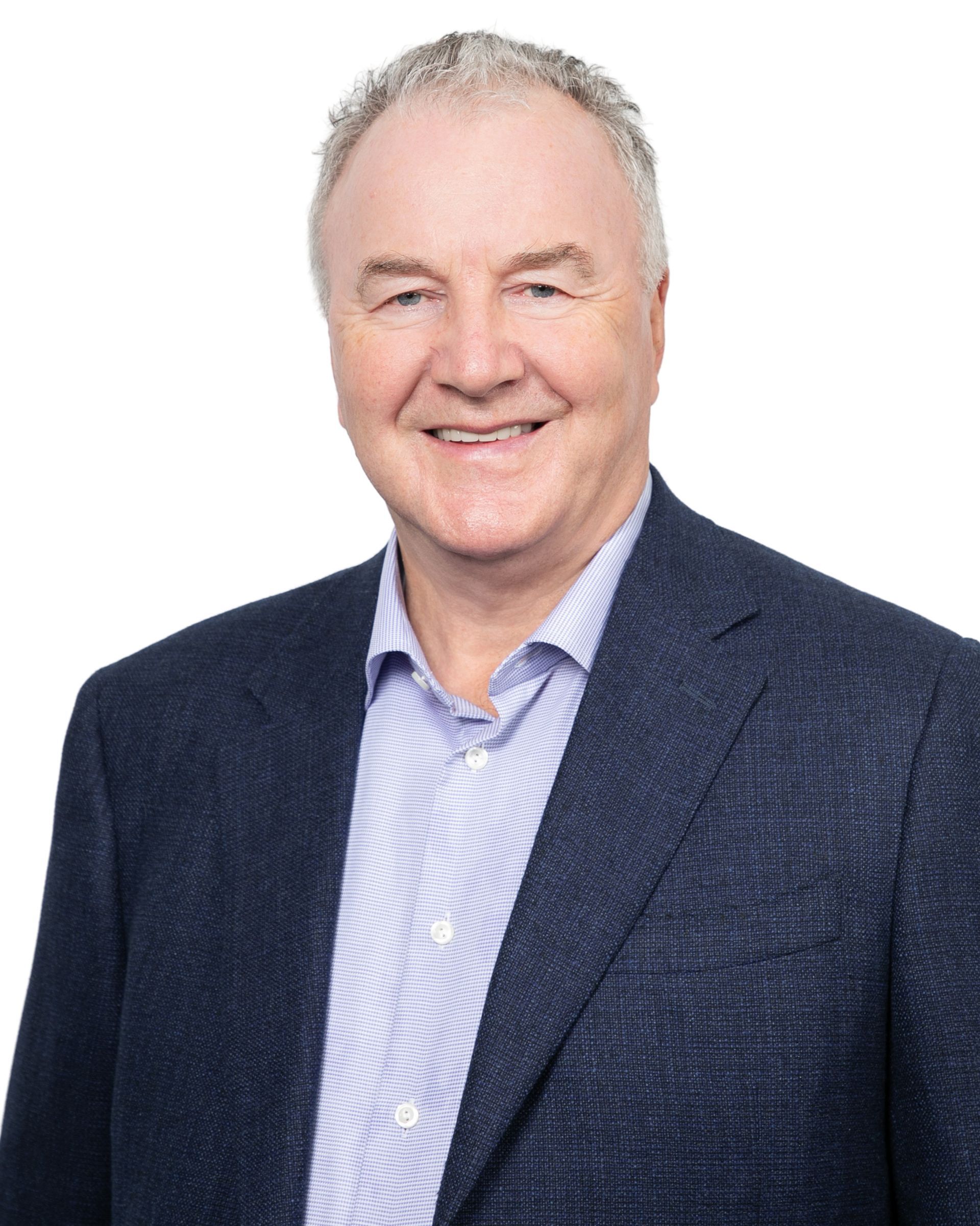 Smiling man in a navy blazer and striped shirt against a white background