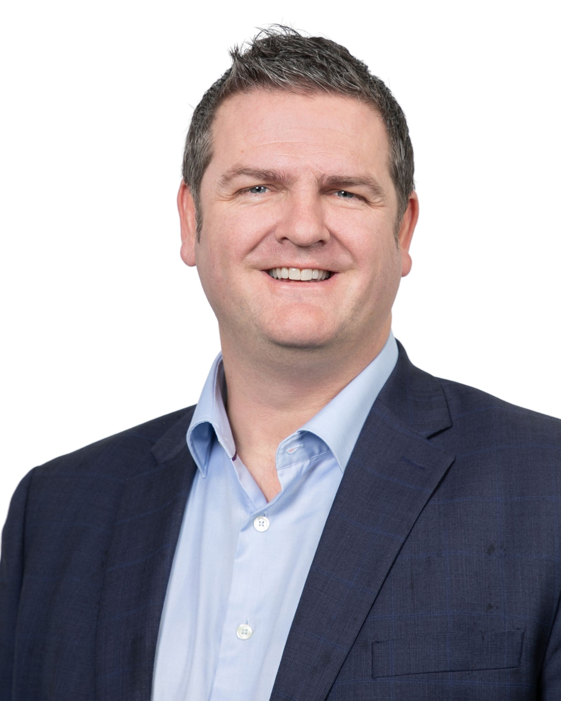 Smiling man in a navy blazer and light blue shirt against a white background