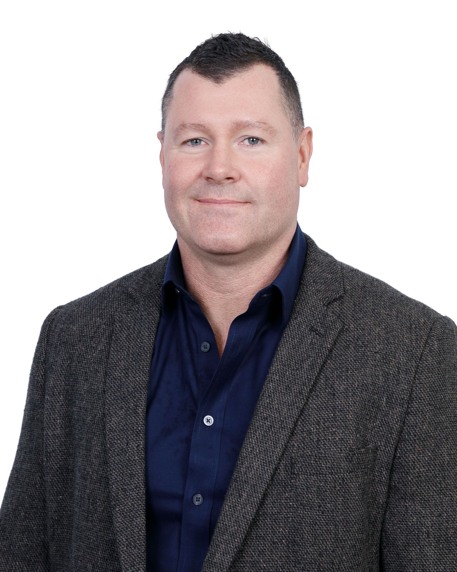 Studio portrait of a person in a dark blazer and navy shirt against a white background