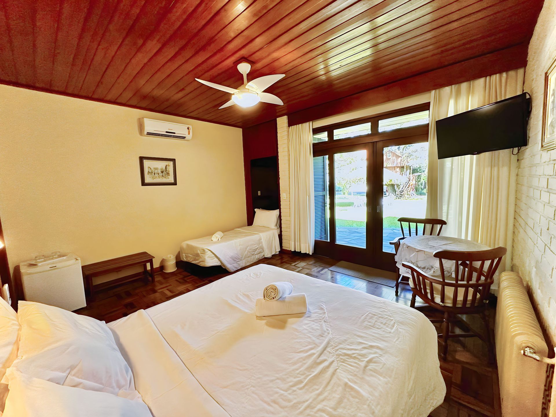 Um quarto com cama, cadeiras, mesa e ventilador de teto.