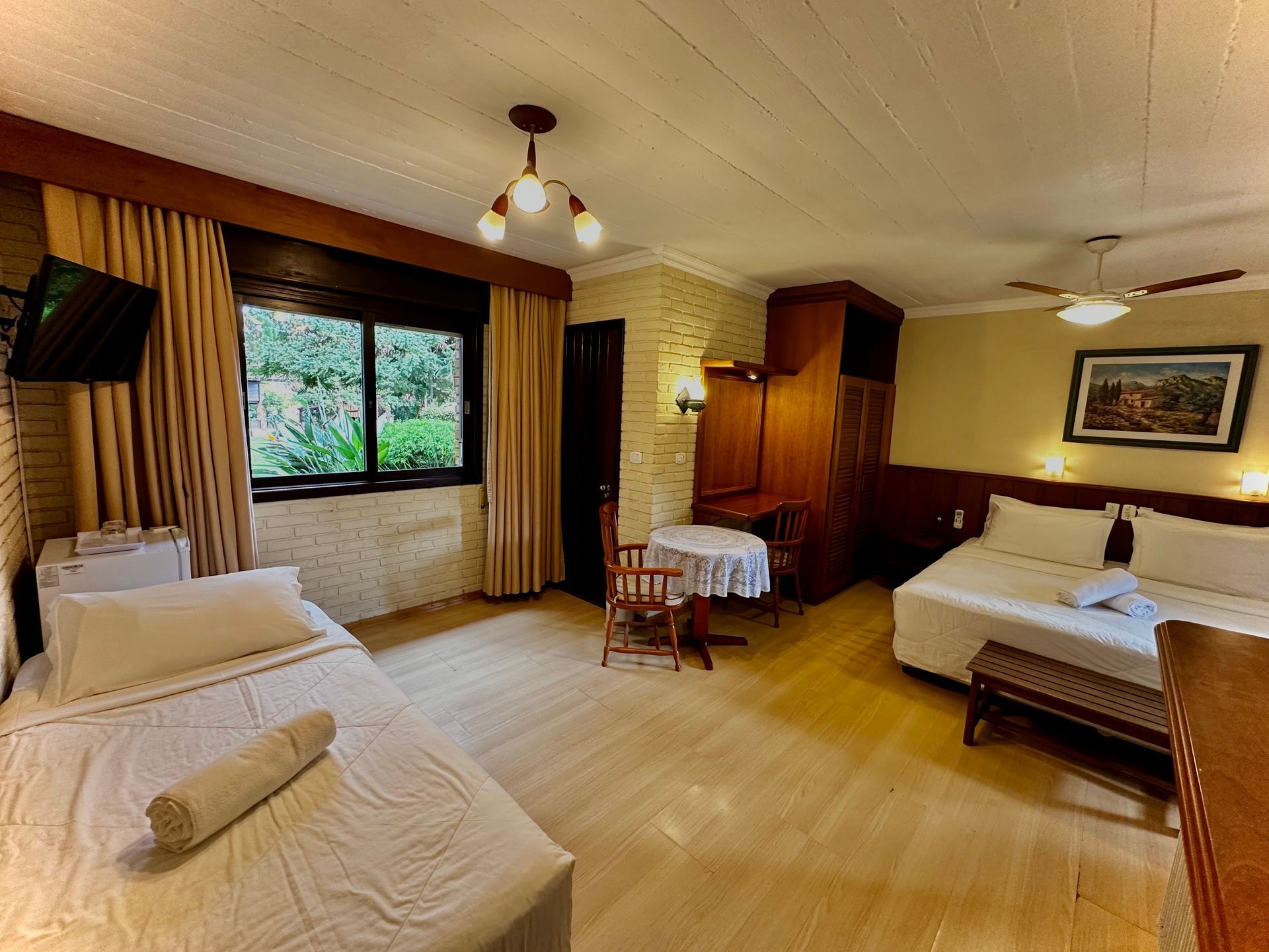 Um quarto de hotel com duas camas, uma mesa e uma janela.