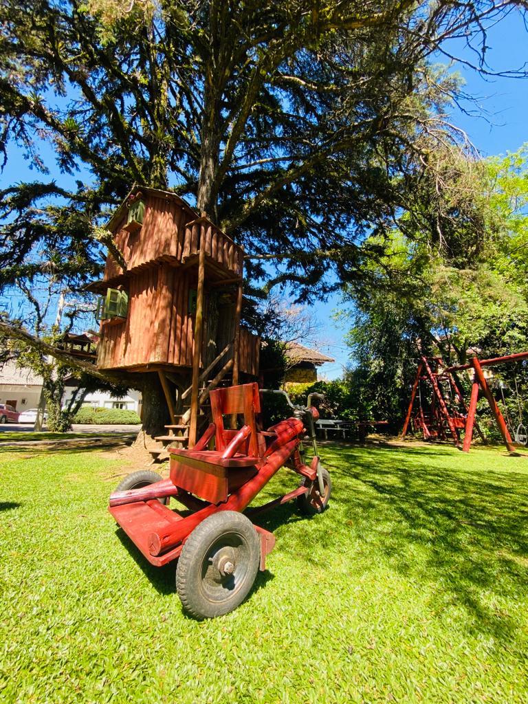 Uma casa na árvore está em cima de um trator vermelho em um parque.