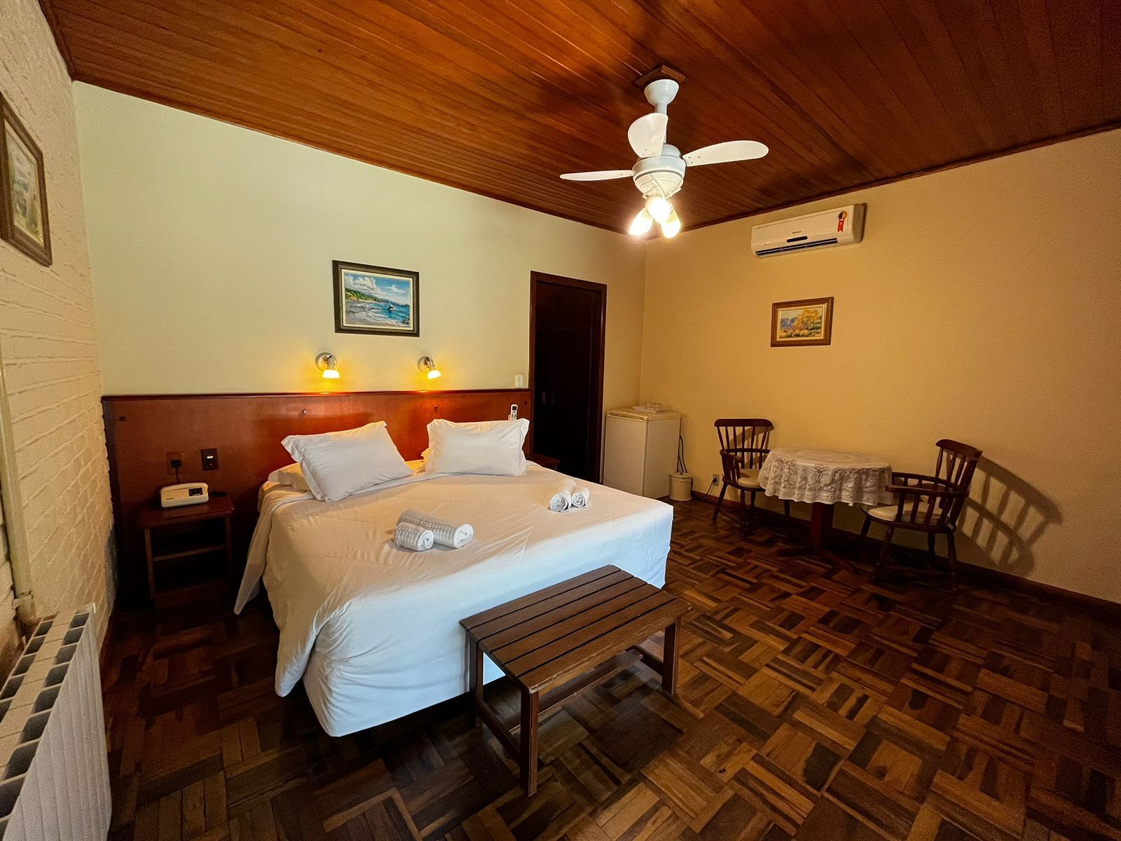 Um quarto de hotel com cama, mesa e cadeiras e ventilador de teto.