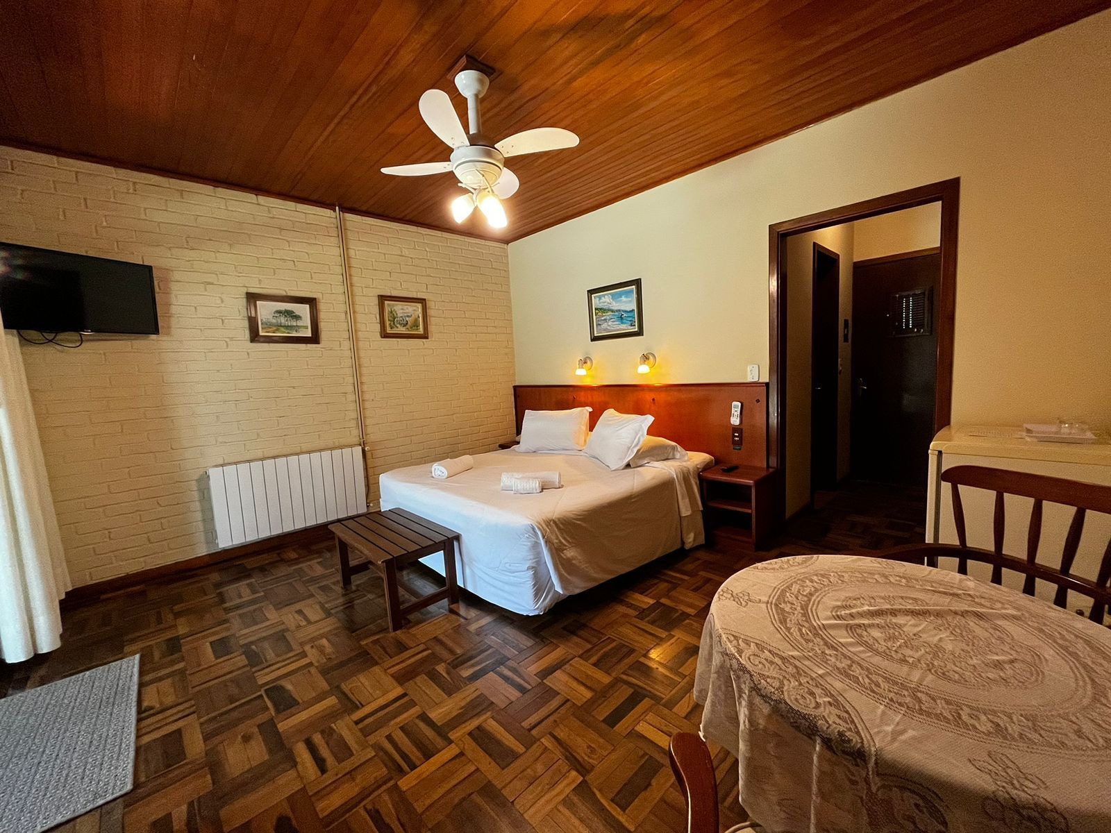 Um quarto de hotel com cama, mesa, cadeiras e ventilador de teto.