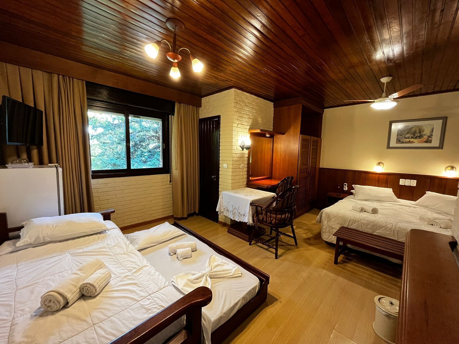 Um quarto de hotel com duas camas, uma mesa e um ventilador de teto.