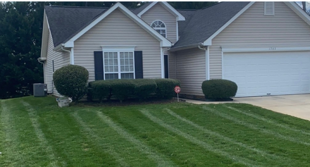 A house with a lush green lawn in front of it.