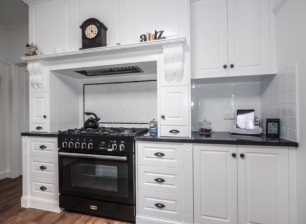 White kitchen with black stove, marble countertop, and white cabinets