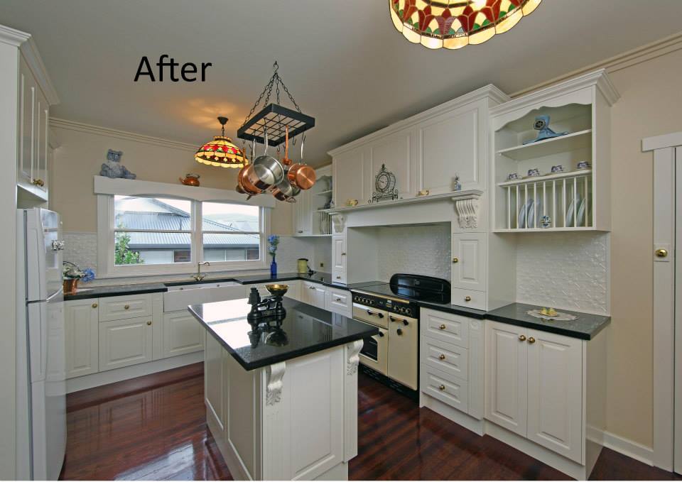 Bright modern kitchen with white cabinets, black countertops, island, and hanging pendant lights