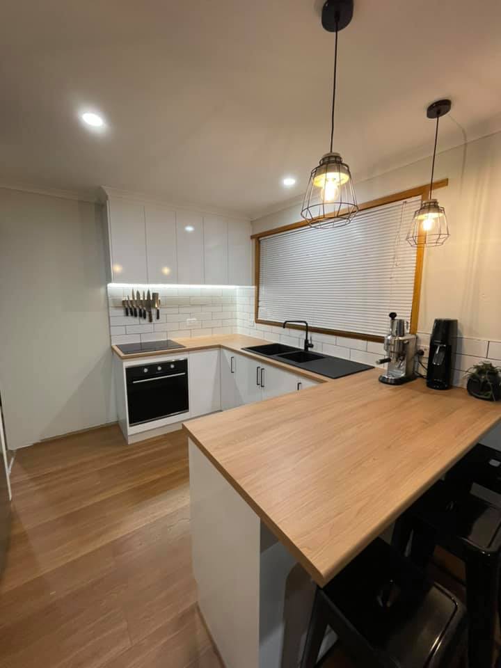 Modern kitchen with white cabinets, wood floors, black appliances, and a wooden island countertop
