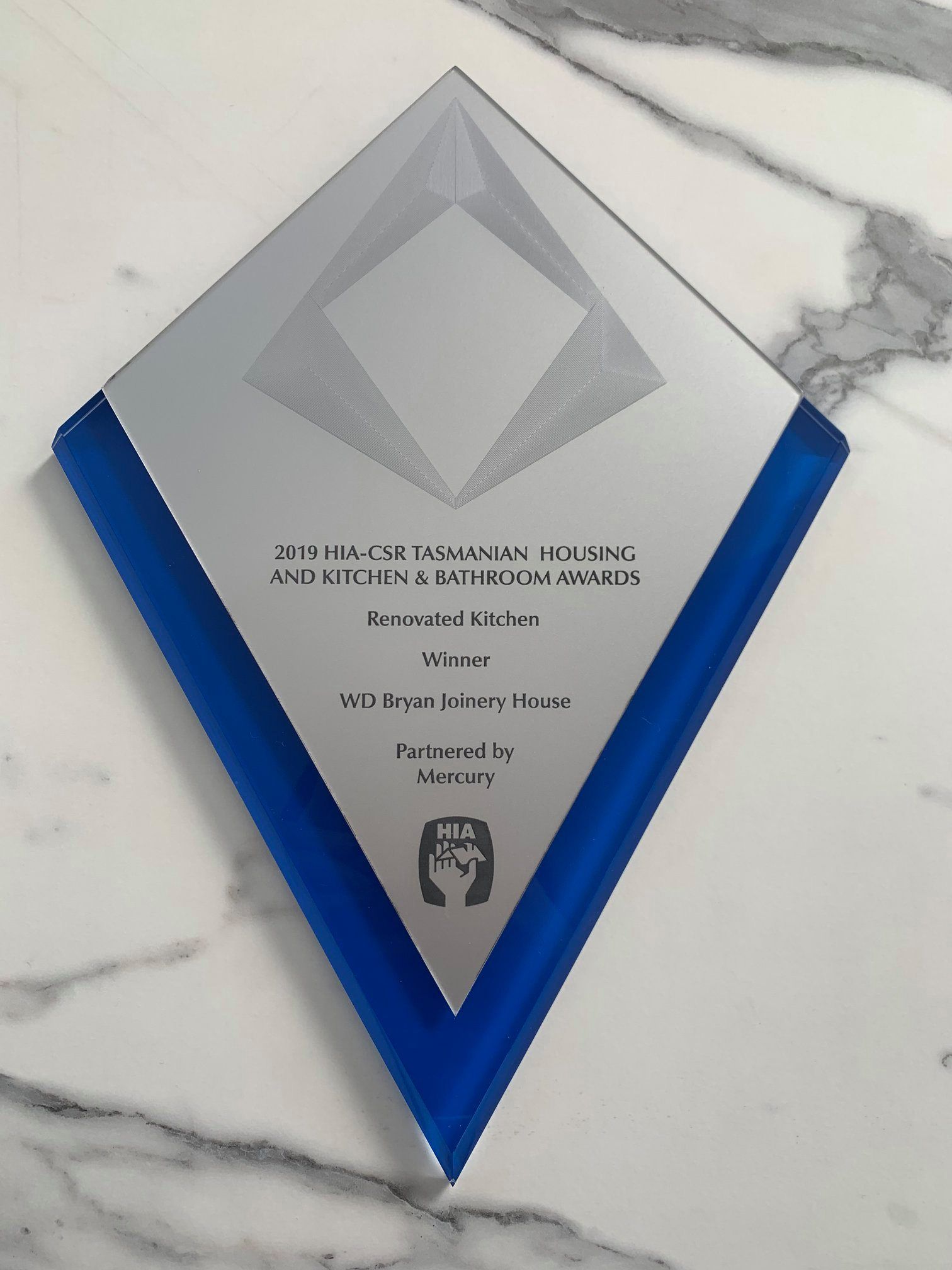 Silver award plaque with a blue border on a marble surface.