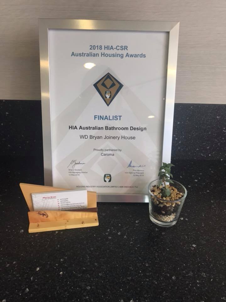 Framed Australian Housing Awards finalist certificate with small potted succulent and envelope on a black counter