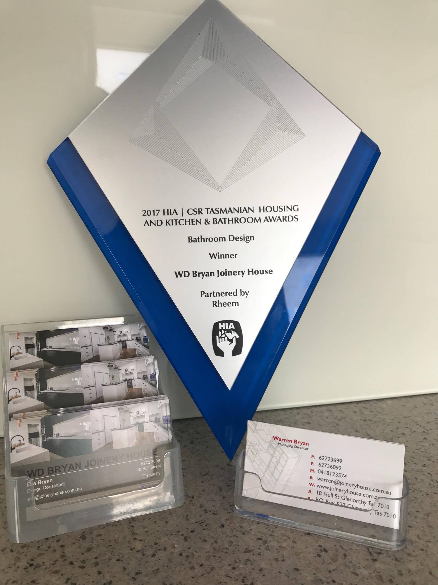 Award plaque in blue frame with a clear brochure holder and business cards on a countertop.