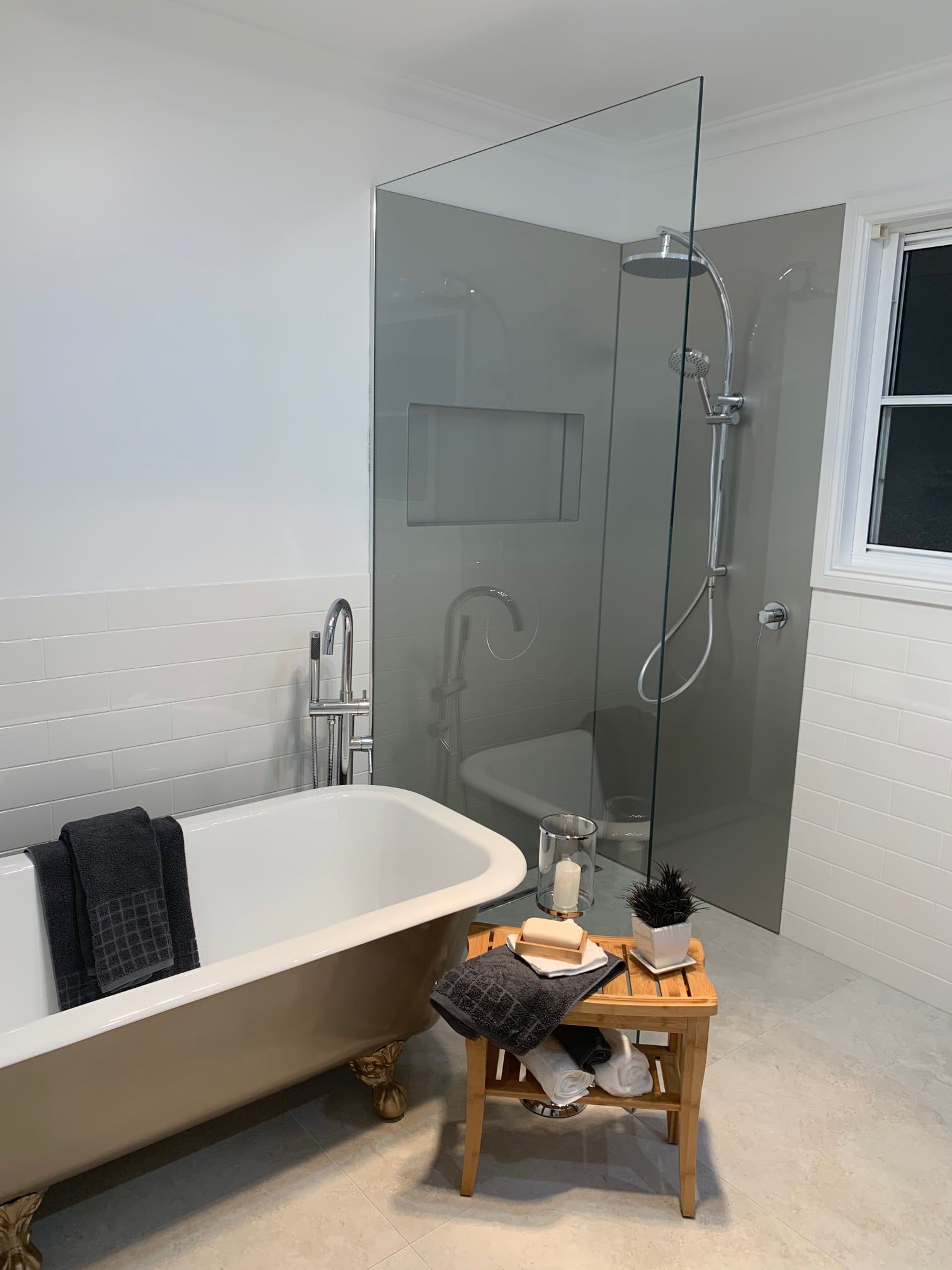 Modern bathroom with freestanding tub, glass shower, and small wooden stool in the center