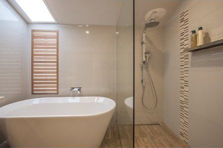 Modern bathroom with freestanding tub, glass shower, and wood accents