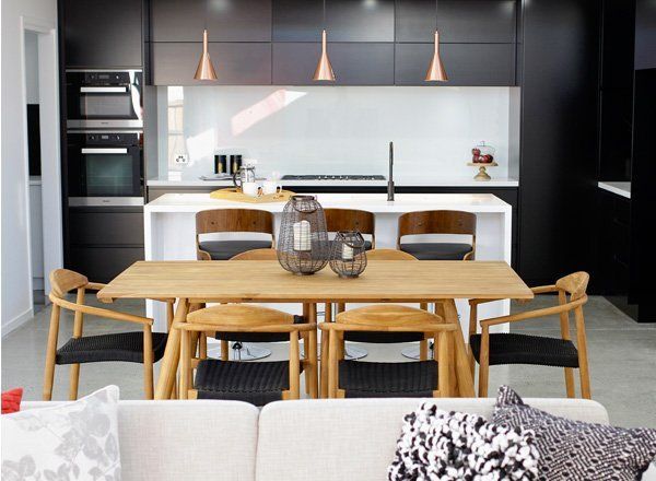 Modern kitchen and dining area with wooden table, white island, and black cabinetry