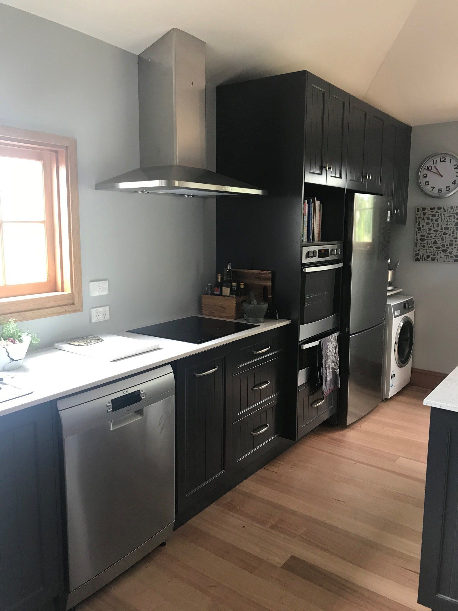 Modern kitchen with black cabinets, stainless appliances, and a washer by a window.
