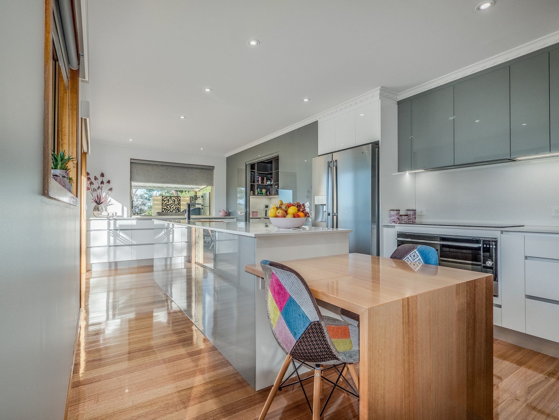Bright modern kitchen with white cabinets, wood island, and colorful chair accents
