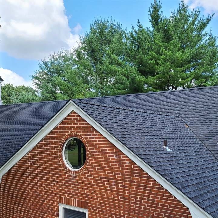 A brick house with a black roof and a round window.