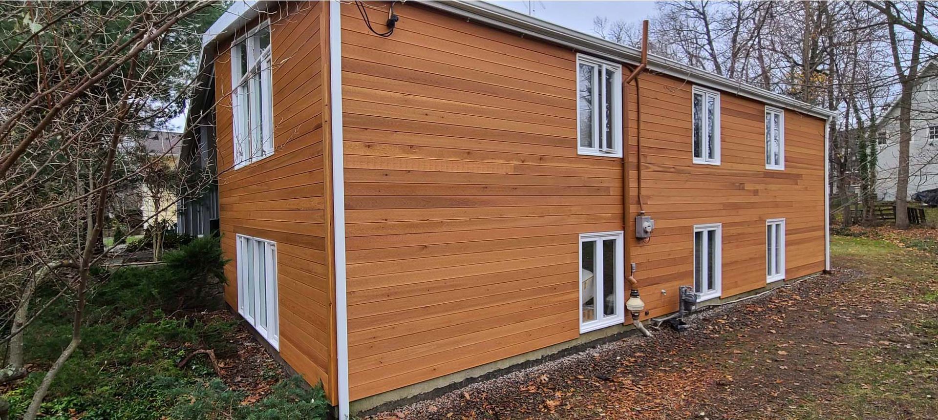 A large wooden house with a lot of windows is surrounded by trees.