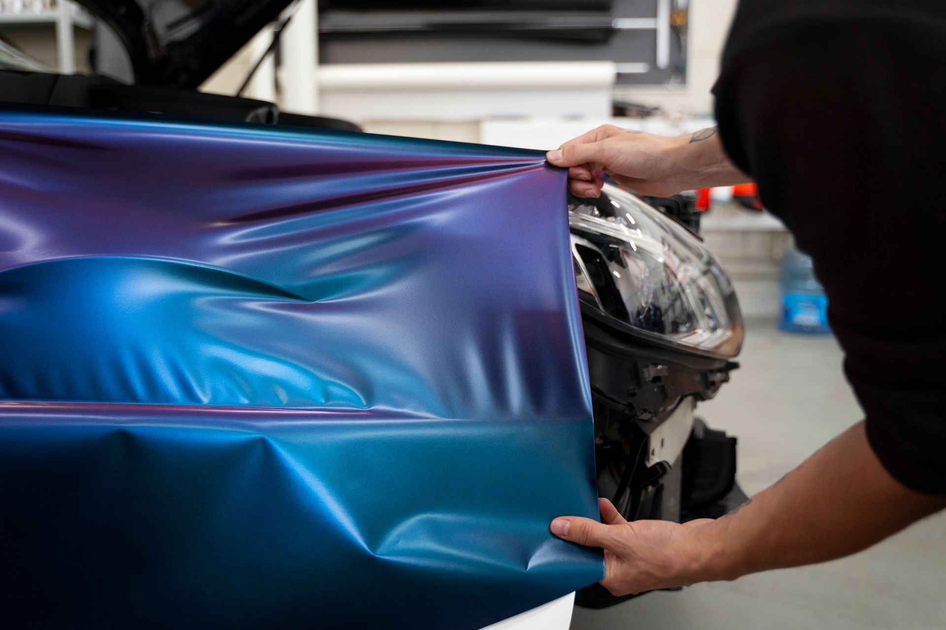 A person is wrapping a car with a blue and purple wrap.