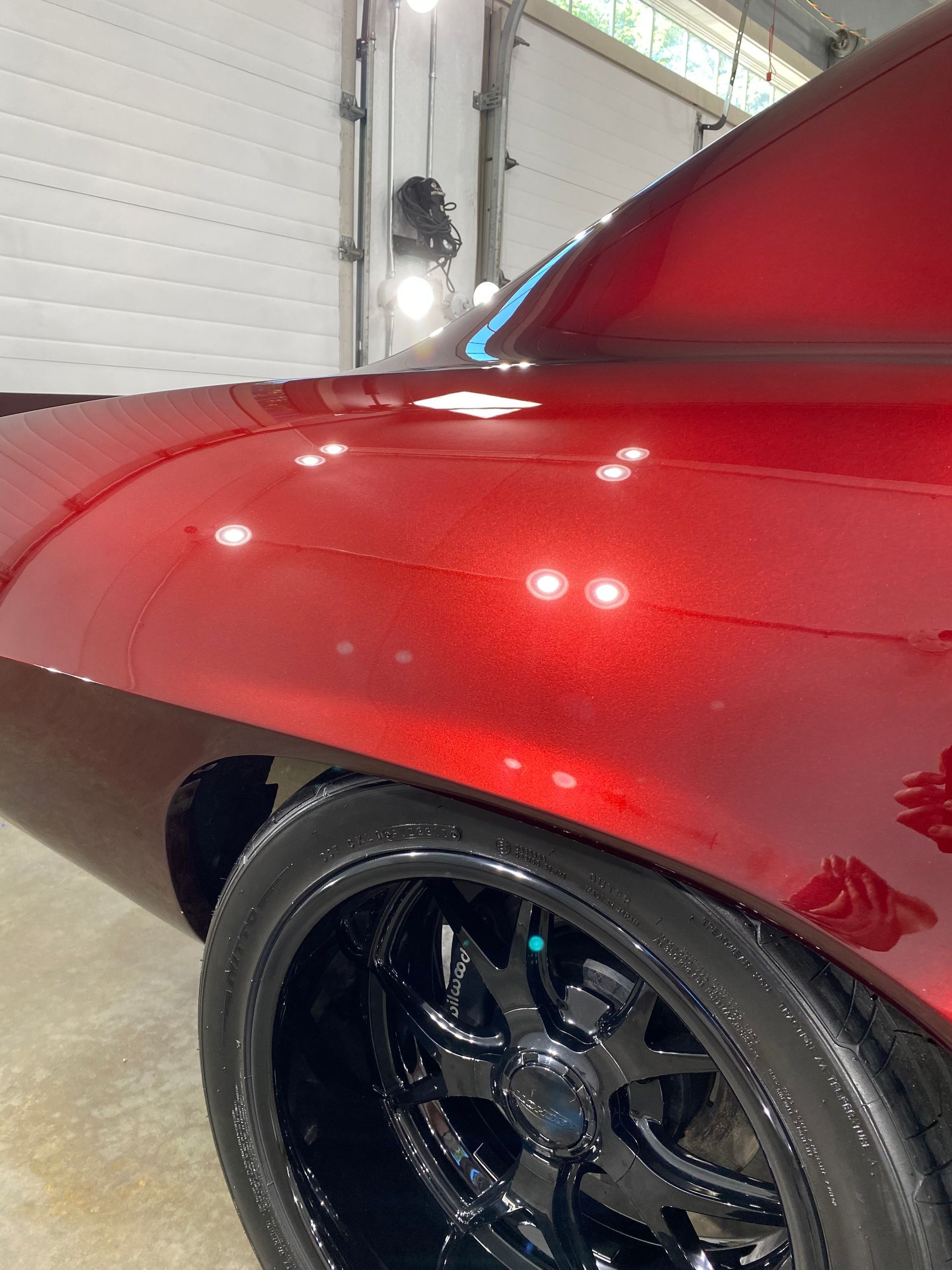 A red car with black wheels is parked in a garage.