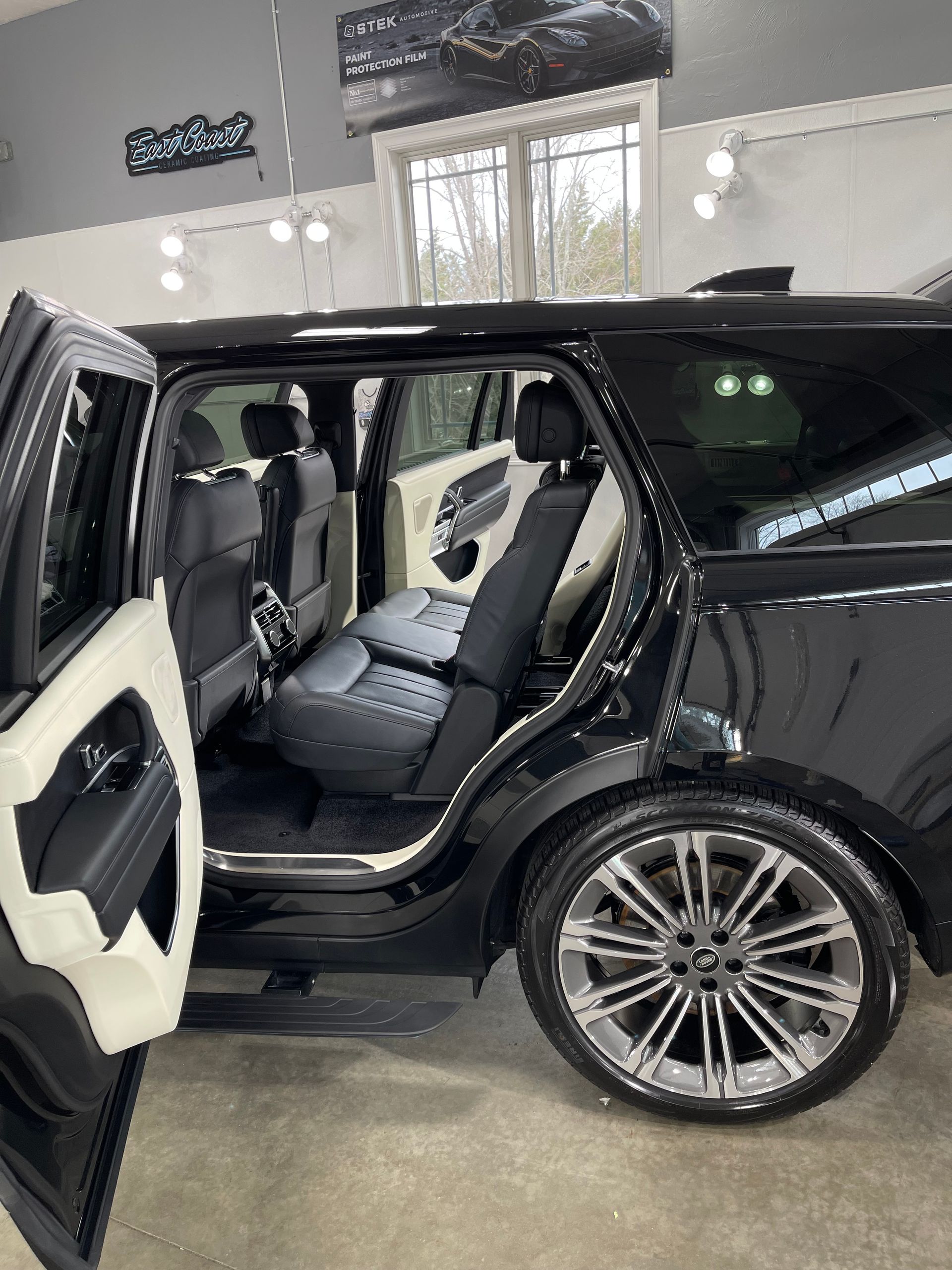 A black range rover is parked in a garage with its doors open.