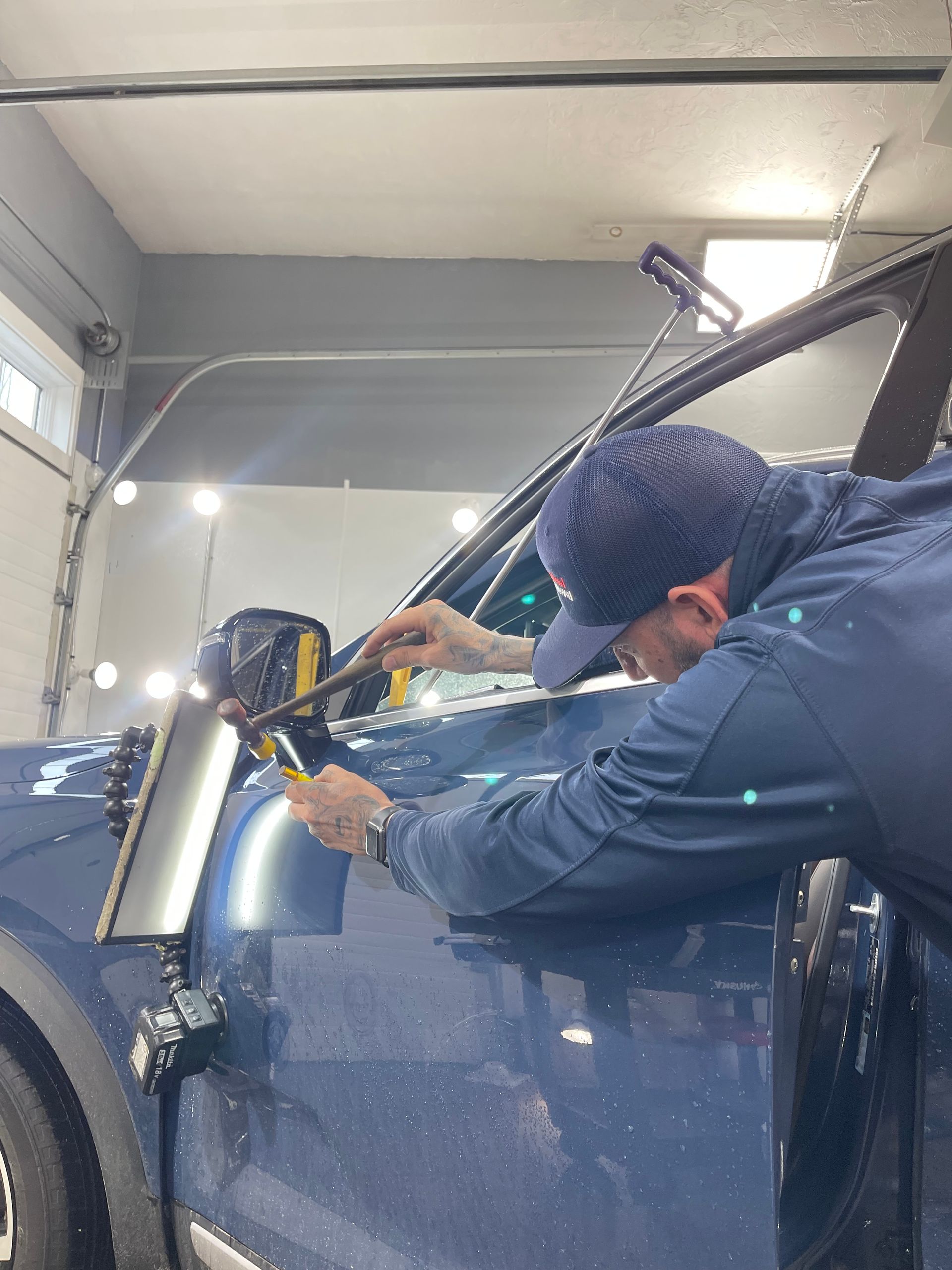 A man is working on a blue car in a garage.