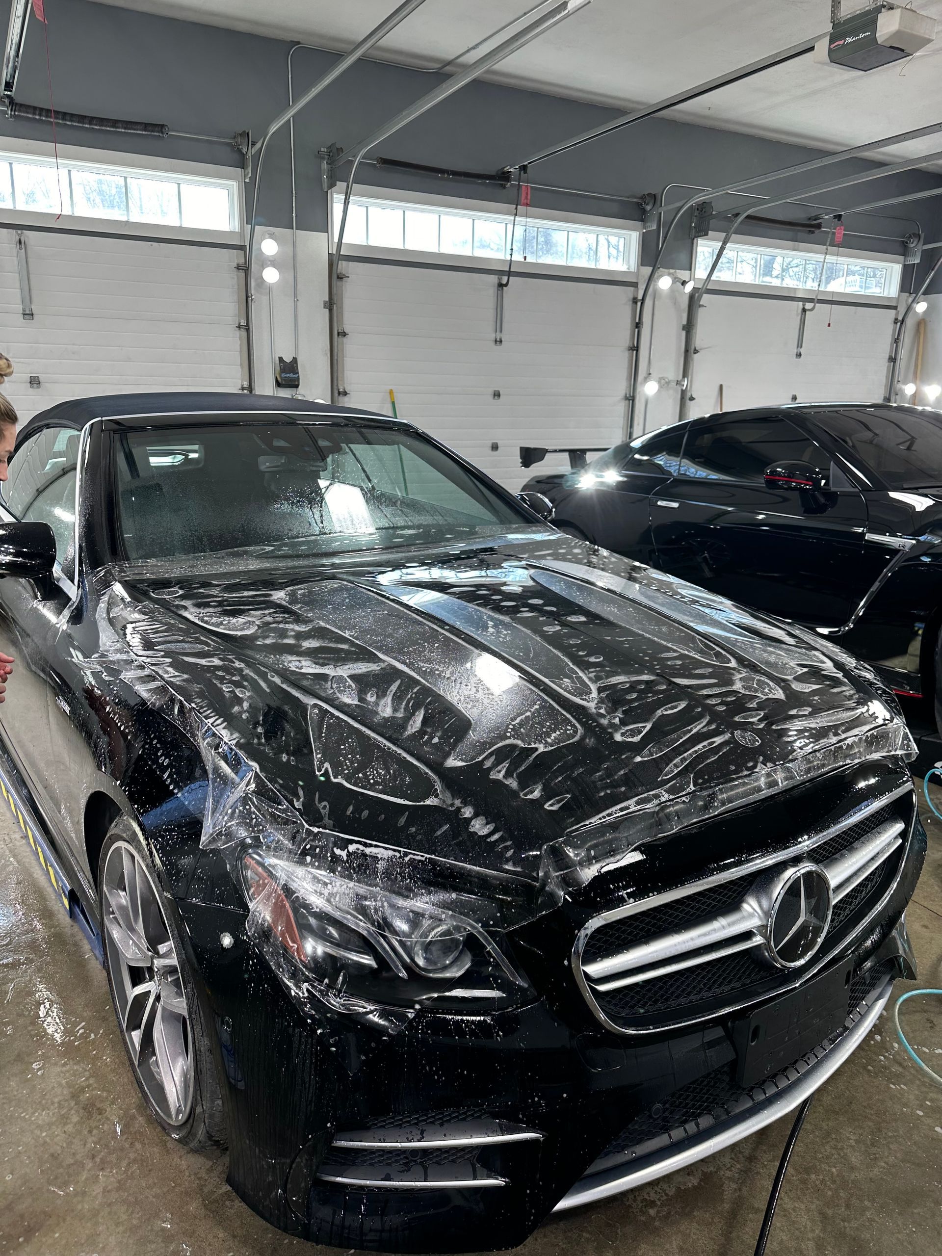 A black mercedes benz sl63 convertible is sitting in a garage.